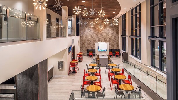 A spacious indoor area with multiple tables and chairs, a brick wall, and hanging star-shaped lights. - Residence Inn Pittsburgh Oakland/University Place (Pittsburgh)