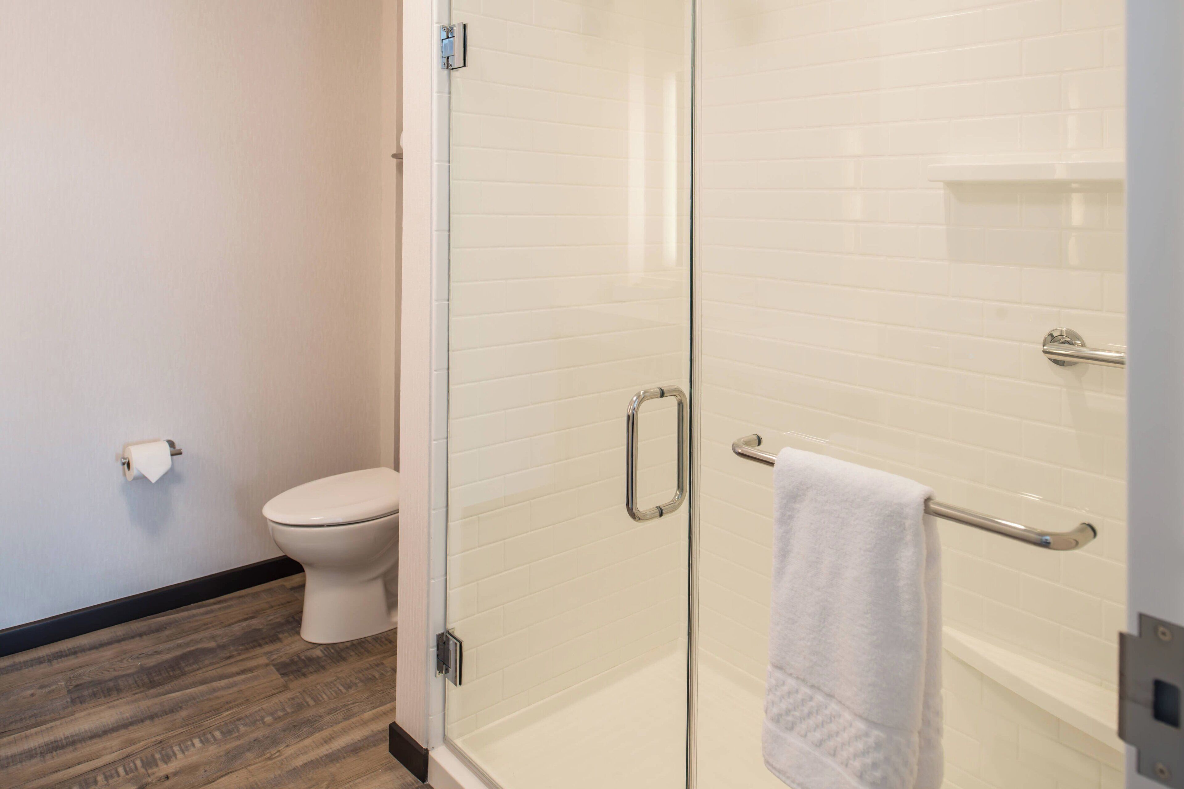 Un baño con cabina de ducha de vidrio, inodoro blanco y un perchero para toallas.