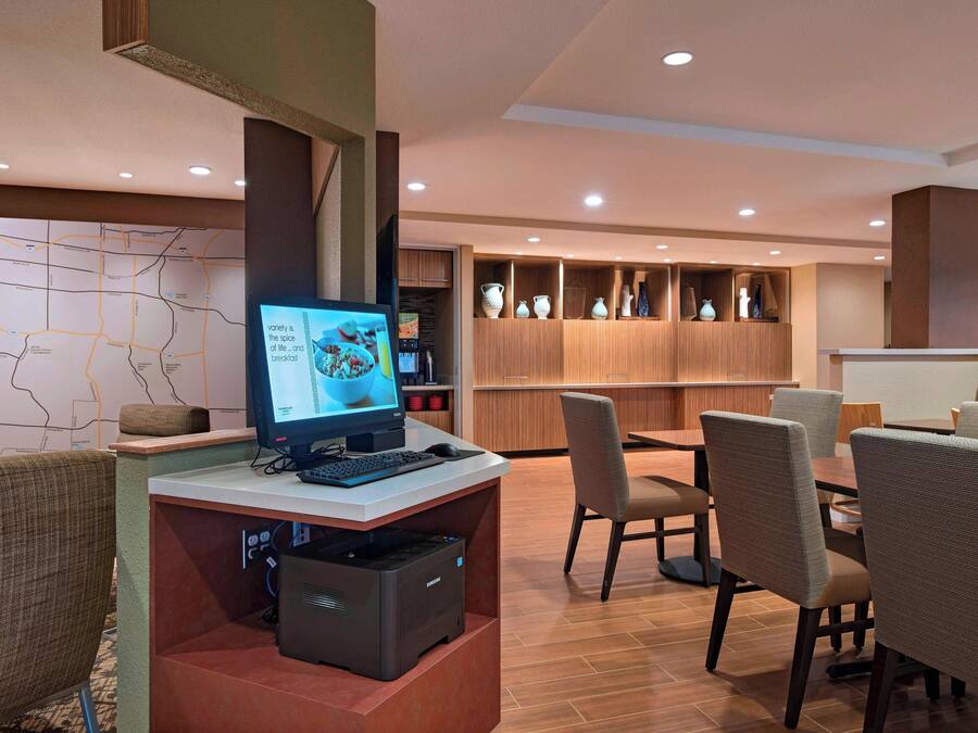Un hall de hotel con recepción, computadora, impresora y zona de estar.