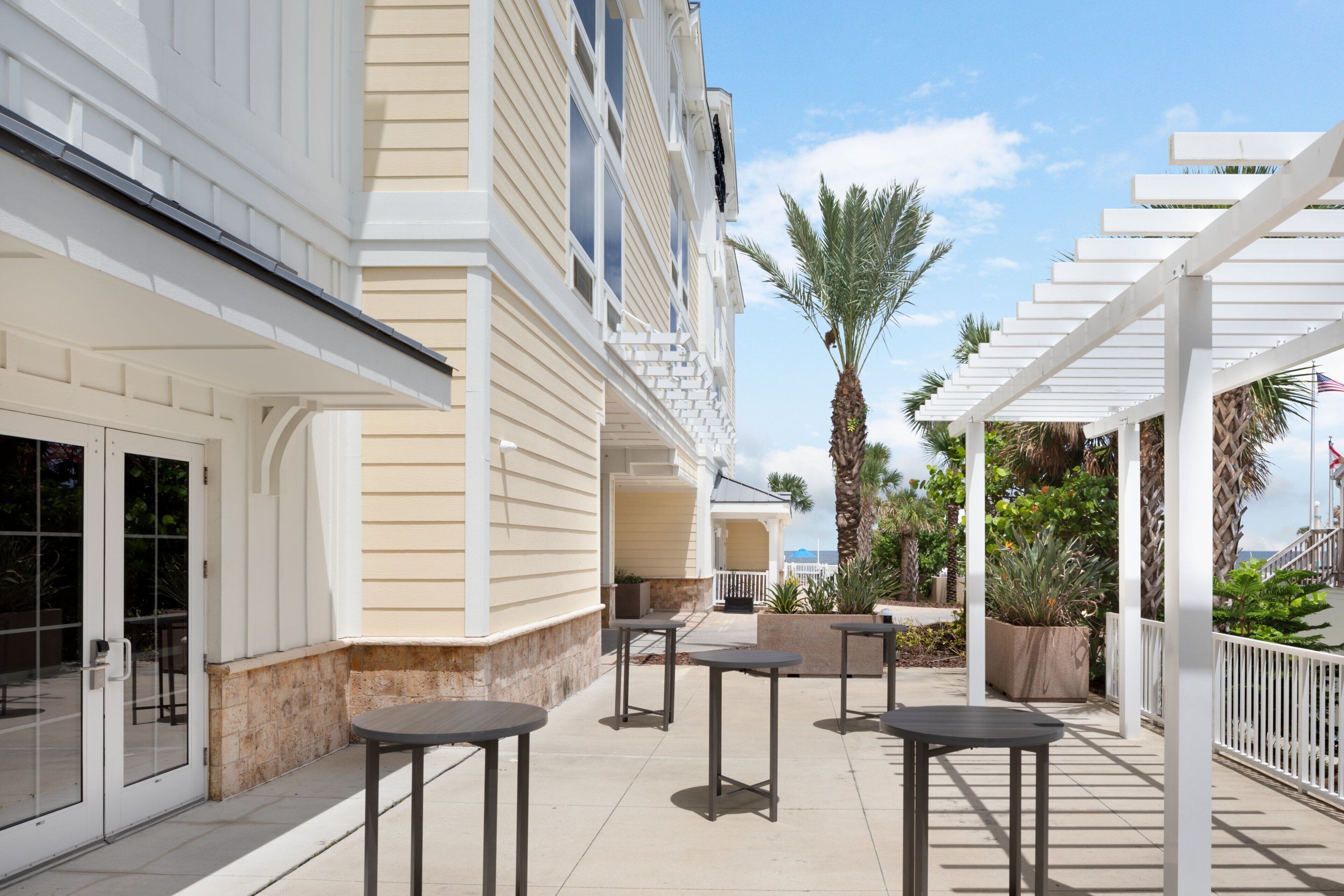 Een hotelterras met zitplaatsen buiten, een overdekt gedeelte en uitzicht op zee.