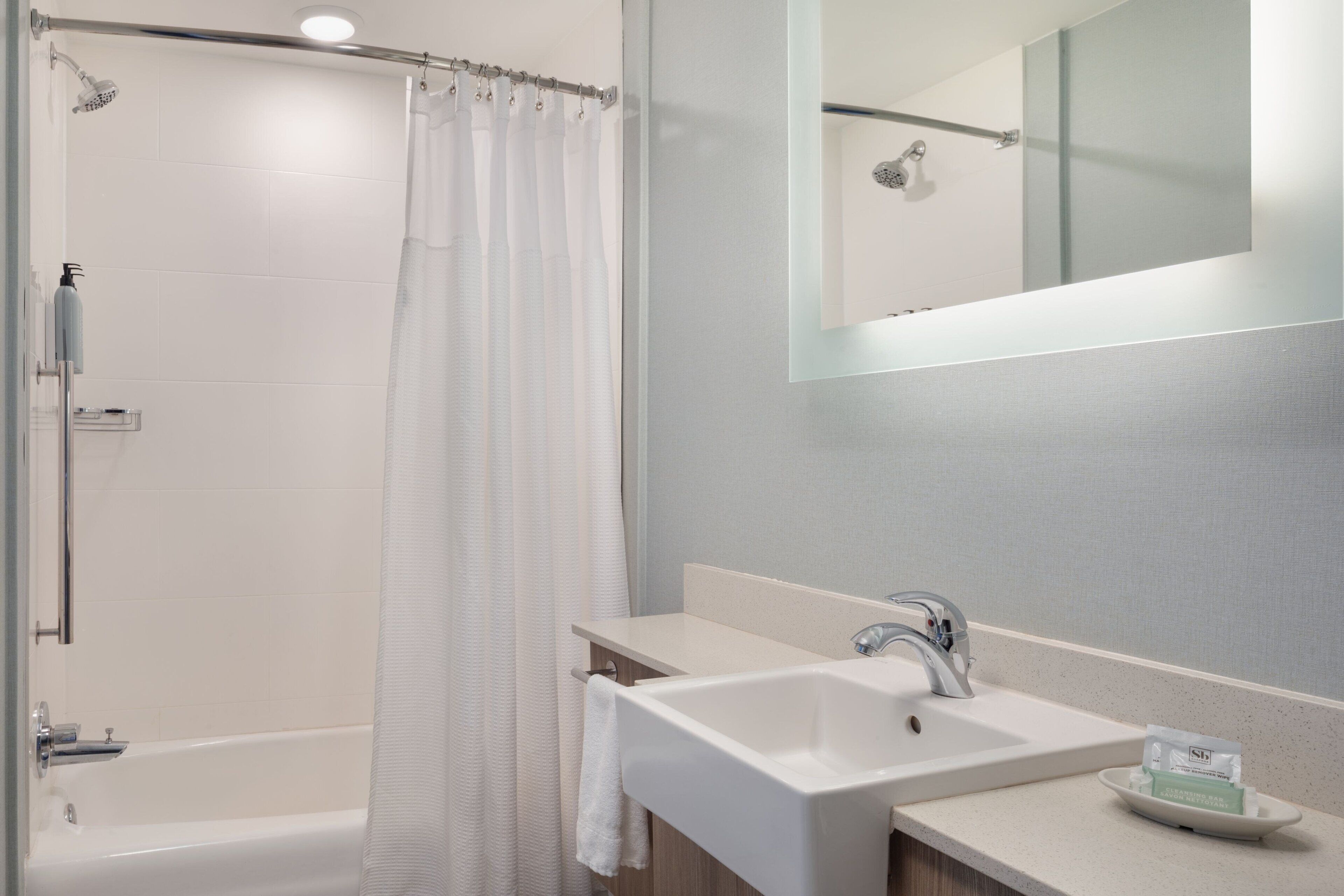 A modern bathroom with a bathtub, shower, and sink.