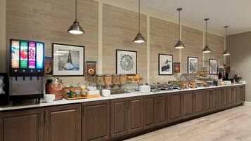 A breakfast bar with a coffee machine, food dispensers, and various breakfast items.