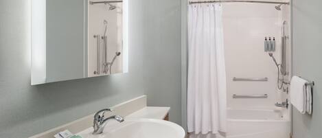 A modern bathroom with a large sink, mirror, shower, and bathtub.
