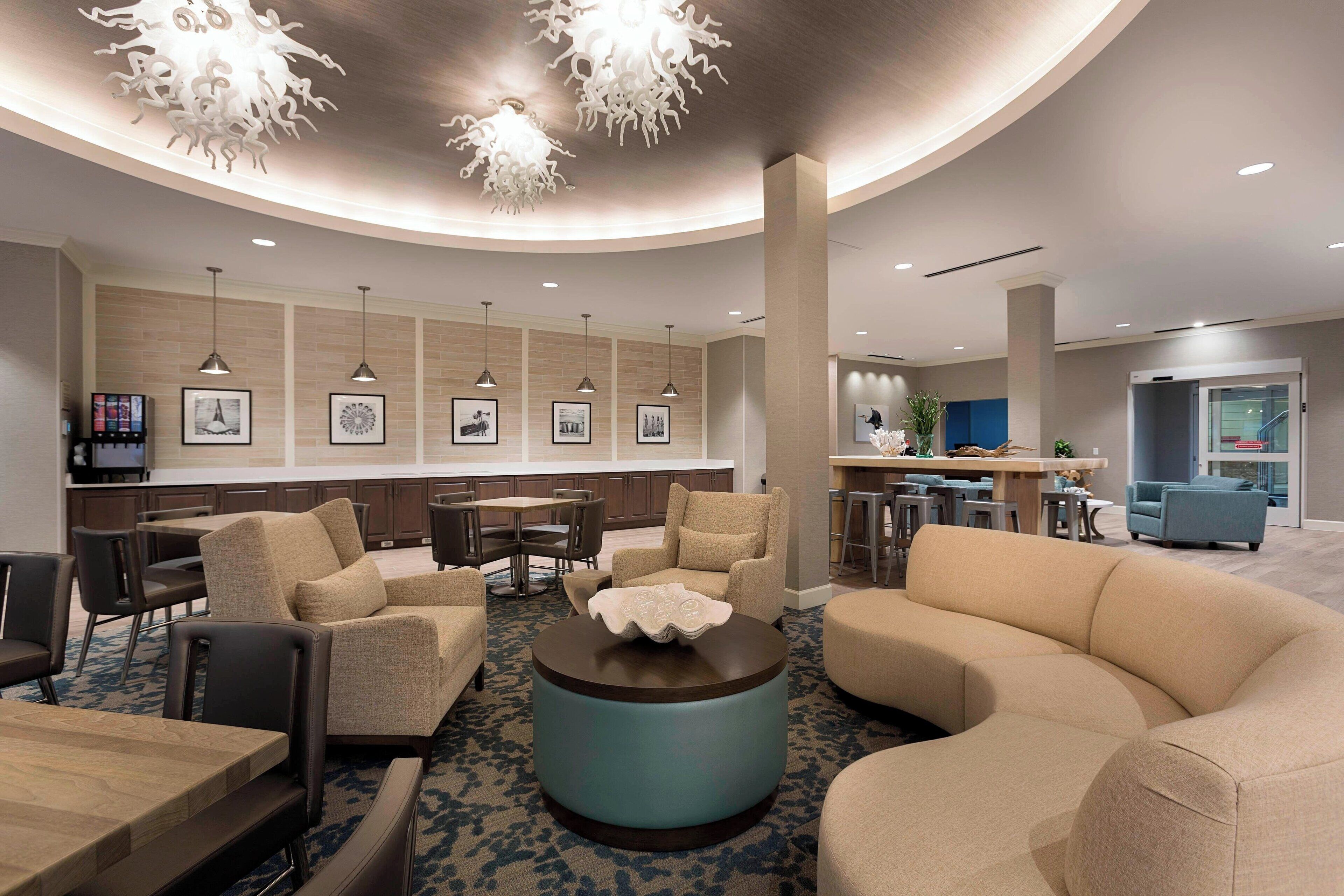 A modern lobby with a curved ceiling, seating areas, a bar, and a dining area.