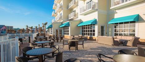 An outdoor patio area with tables and chairs, a pool, and a building with balconies.