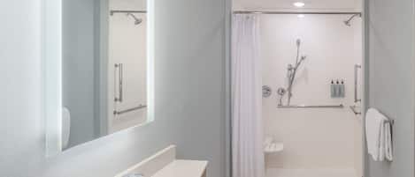 Un baño moderno con lavabo, espejo, ducha e inodoro.