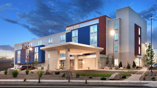 Un hotel moderno con una entrada destacada, amplias ventanas y un área exterior bien cuidada con jardines.