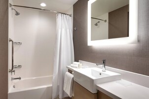 A modern bathroom with a bathtub, shower, and a vanity with a sink and mirror.