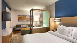 Habitación de hotel con cama, sofá, escritorio, televisión y ventana con vistas.