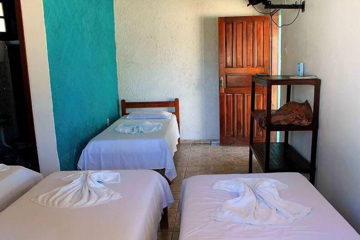 A room with two beds, a wooden door, and a small shelf with items.
