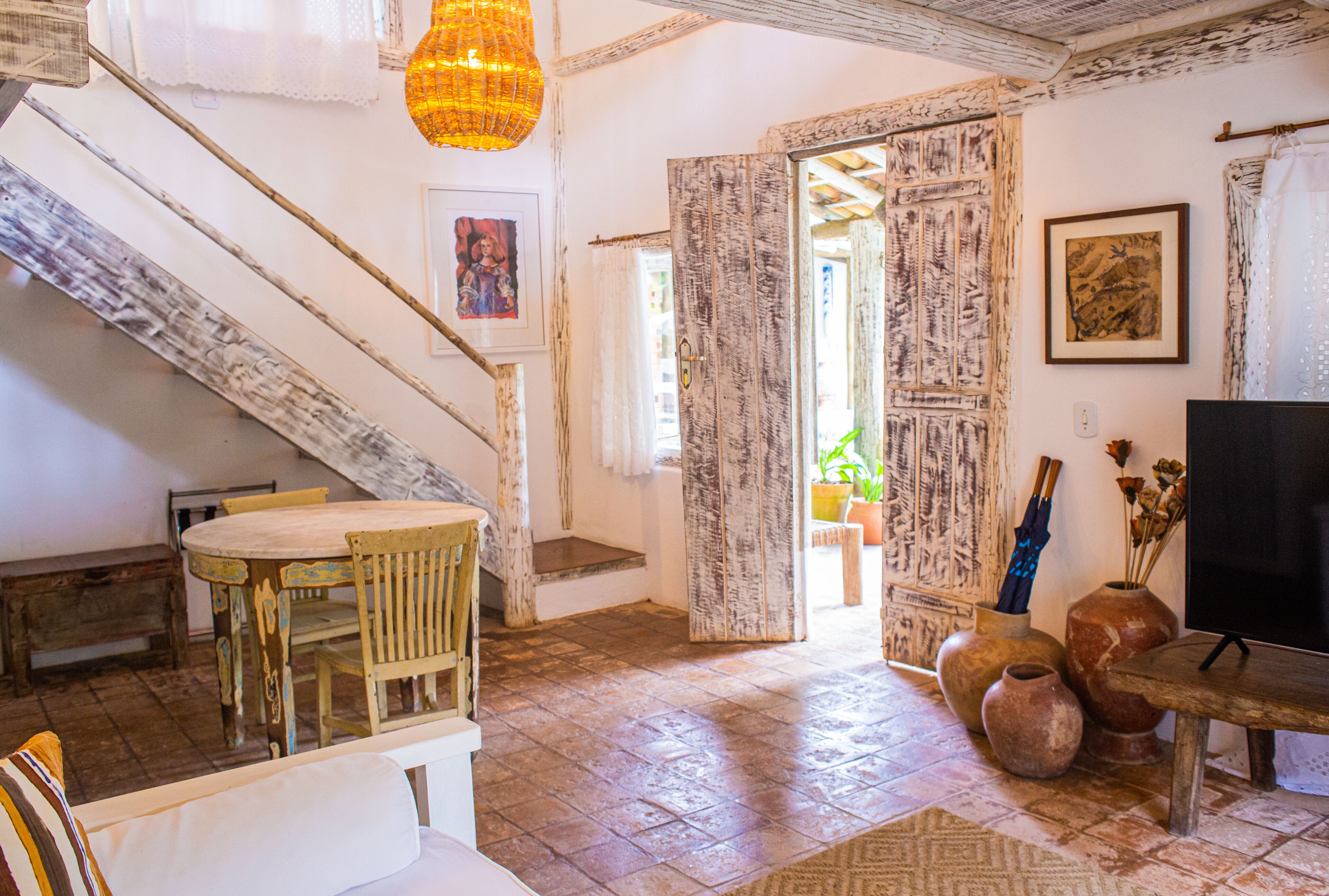 Un interior rústico con una escalera de madera, una zona de comedor y un televisor.
