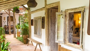 A rustic outdoor patio with a wooden bench, potted plants, and a wooden ceiling structure. - Hotel Boutique Casa de Perainda (Porto Seguro)