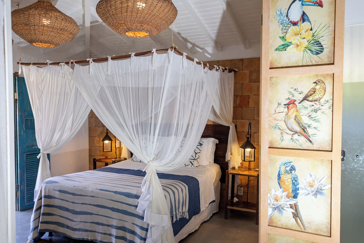 A bedroom with a canopy bed, wooden headboard, and artwork on the wall.
