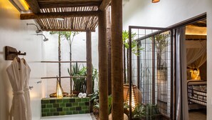 A bathroom with a shower, a bathtub, and a small garden area with plants and a water feature. - Hotel Boutique Casa de Perainda (Porto Seguro)