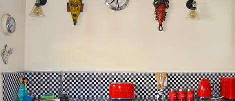 A kitchen with a checkered backsplash, a red toaster, and various kitchen utensils.
