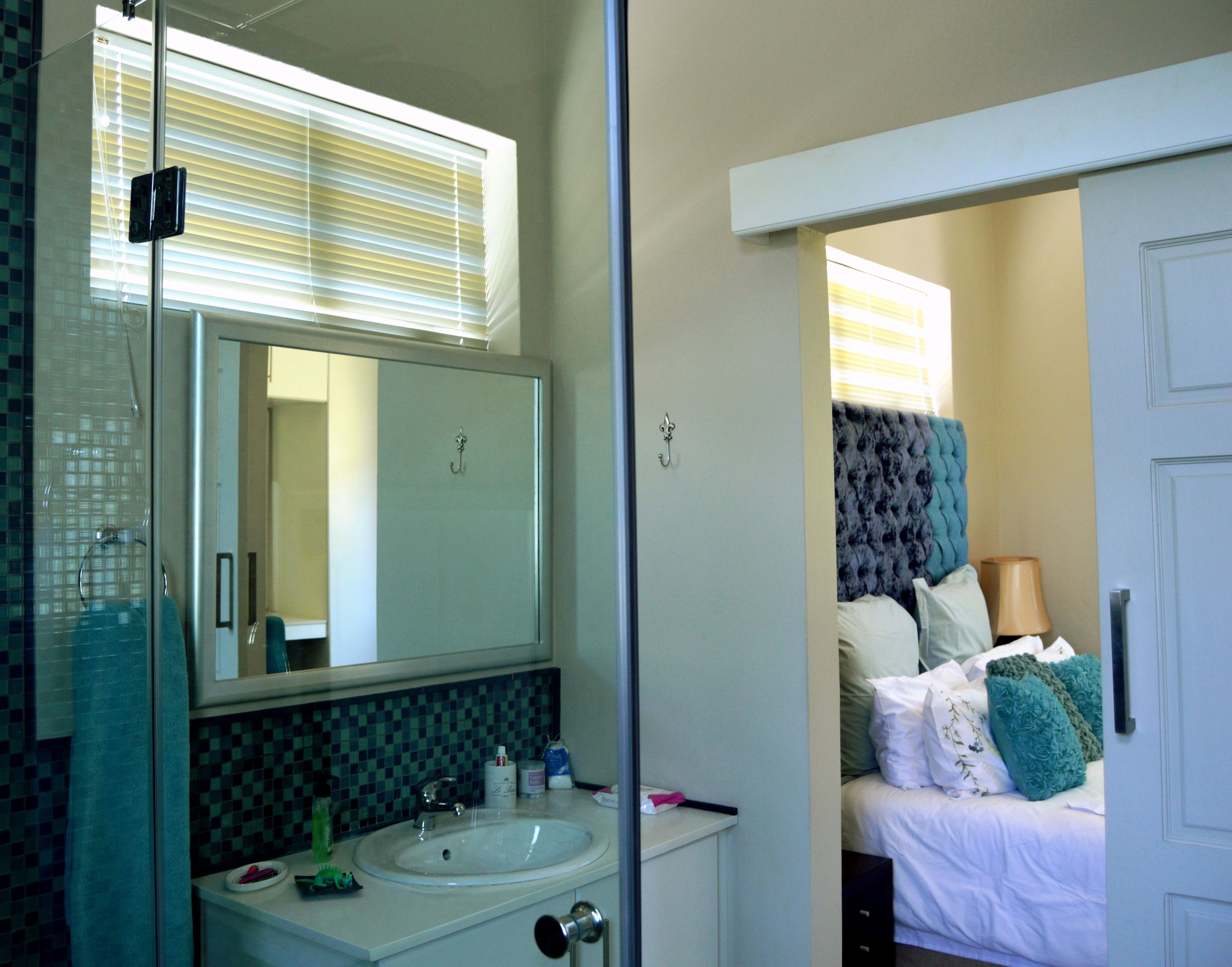 A bathroom with a sink, mirror, and shower.