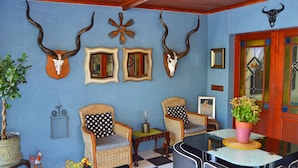 A room with two wicker chairs, a small table, and a potted plant. - 1AA Wilhelminia Apartments (Franschhoek)