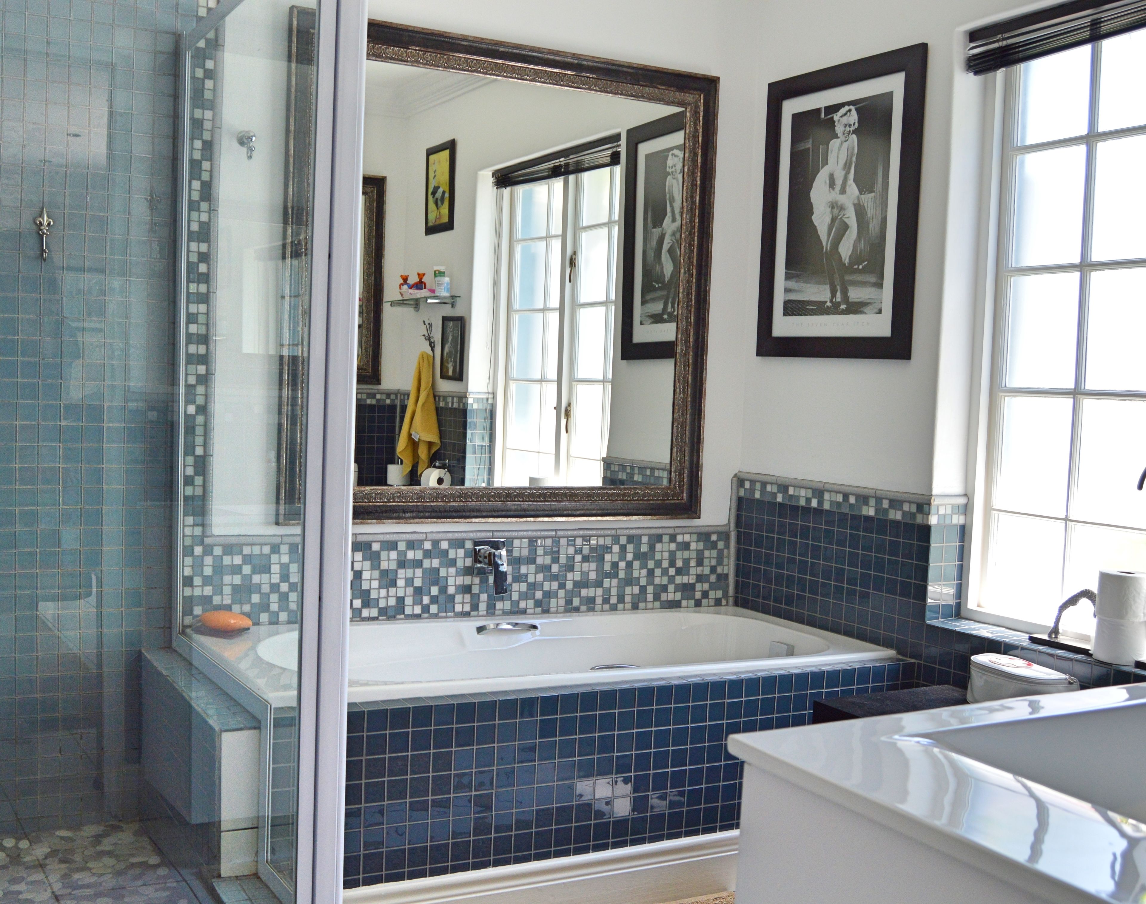 Ein Badezimmer mit einem großen Spiegel, einer Badewanne und einer Toilette.