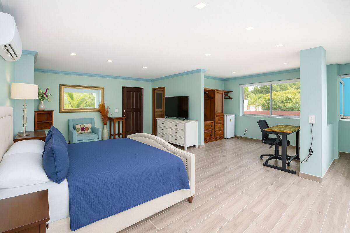 A bedroom with a bed, a desk, a TV, and a wardrobe.