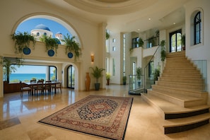 A spacious interior with a grand staircase, a dining area with a view, and a large rug. - Villa Armonia Luxury Suites (Puerto Vallarta)