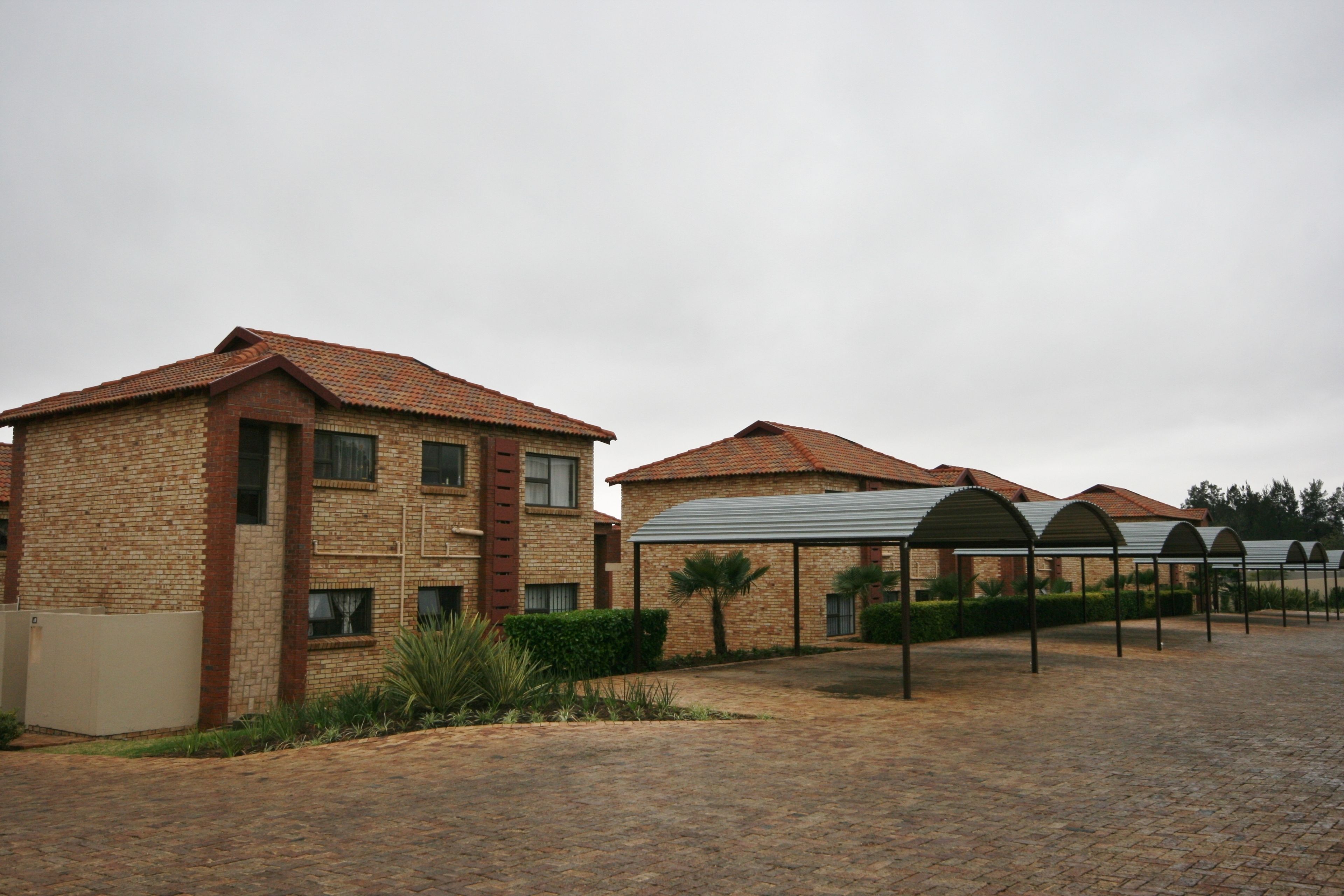A brick building with a tiled roof and a covered outdoor area with metal canopies.