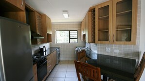 Een keuken met houten kastjes, een roestvrijstalen koelkast, een fornuis en een spoelbak.