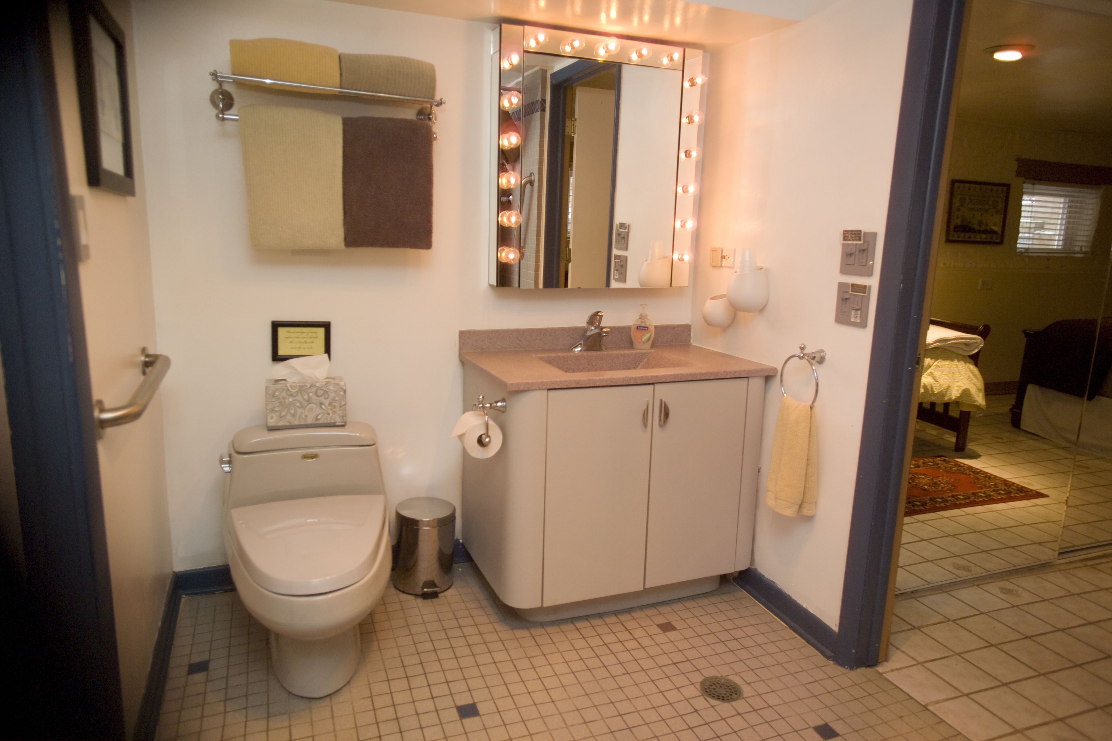 A bathroom with a toilet, sink, mirror, and towel rack.