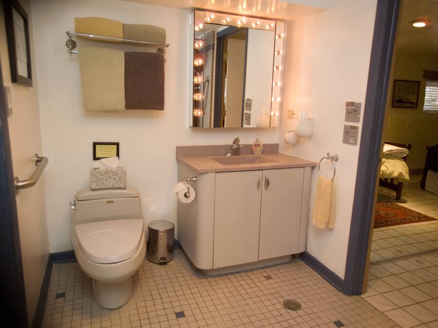 A bathroom with a toilet, sink, mirror, and towel rack.