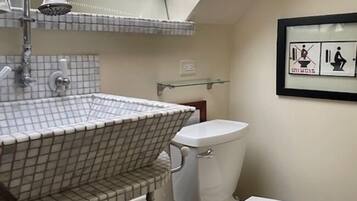 Un baño con tragaluz, un lavamanos con diseño de cuadrícula, un inodoro y un bote de basura.