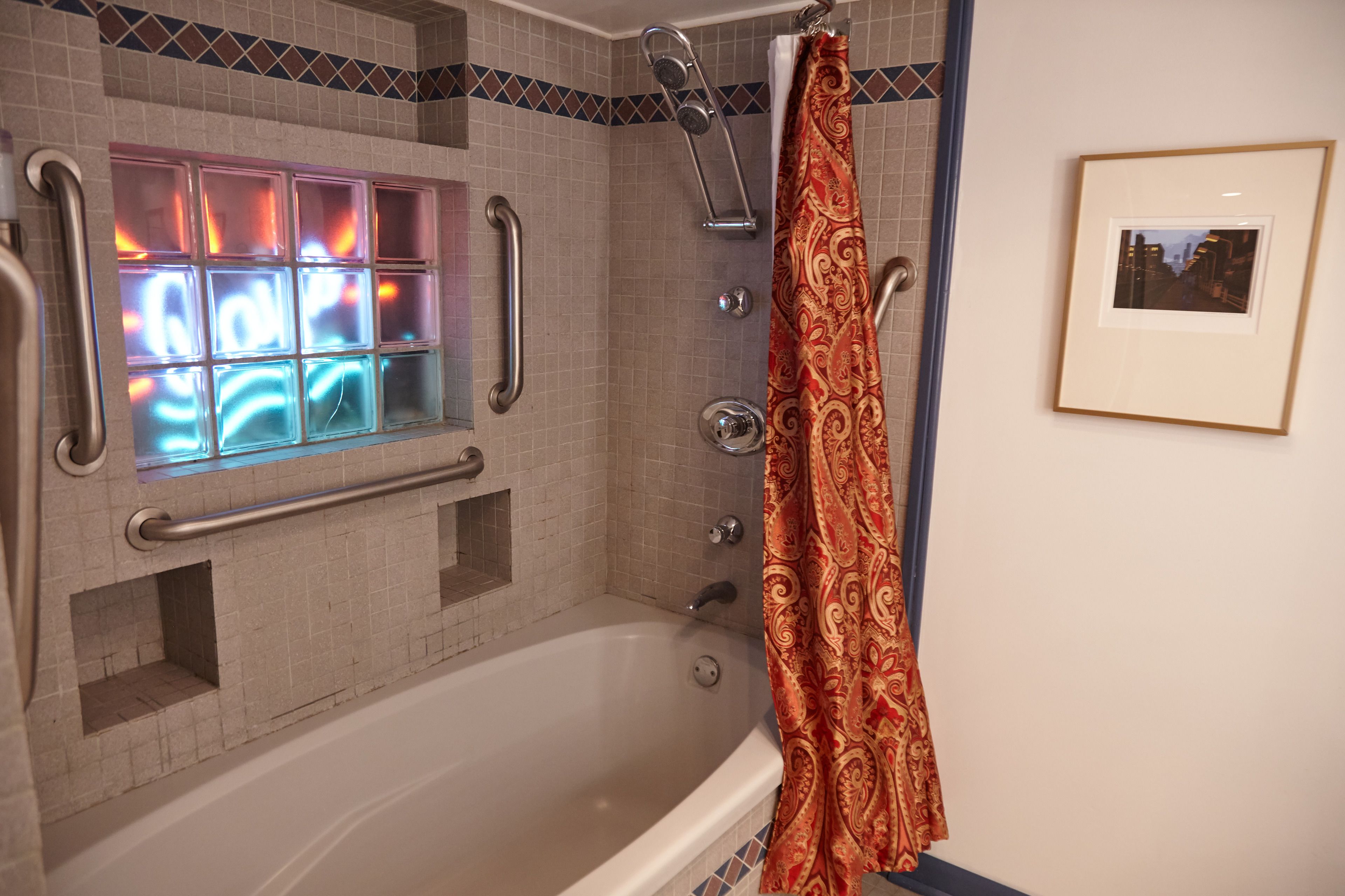 Un baño con bañera, ducha y barras de apoyo.