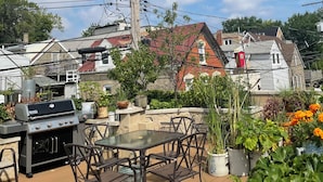 A patio with a grill, outdoor seating, and potted plants. - Ray's Bucktown B&B (Chicago)