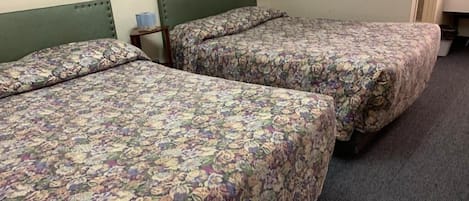 A room with two beds, each with floral-patterned bedding.