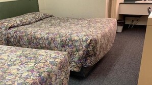 A hotel room with two beds covered in floral-patterned bedding, a small desk with a mirror, and a carpeted floor. - Grey Goose Motel (Castor)