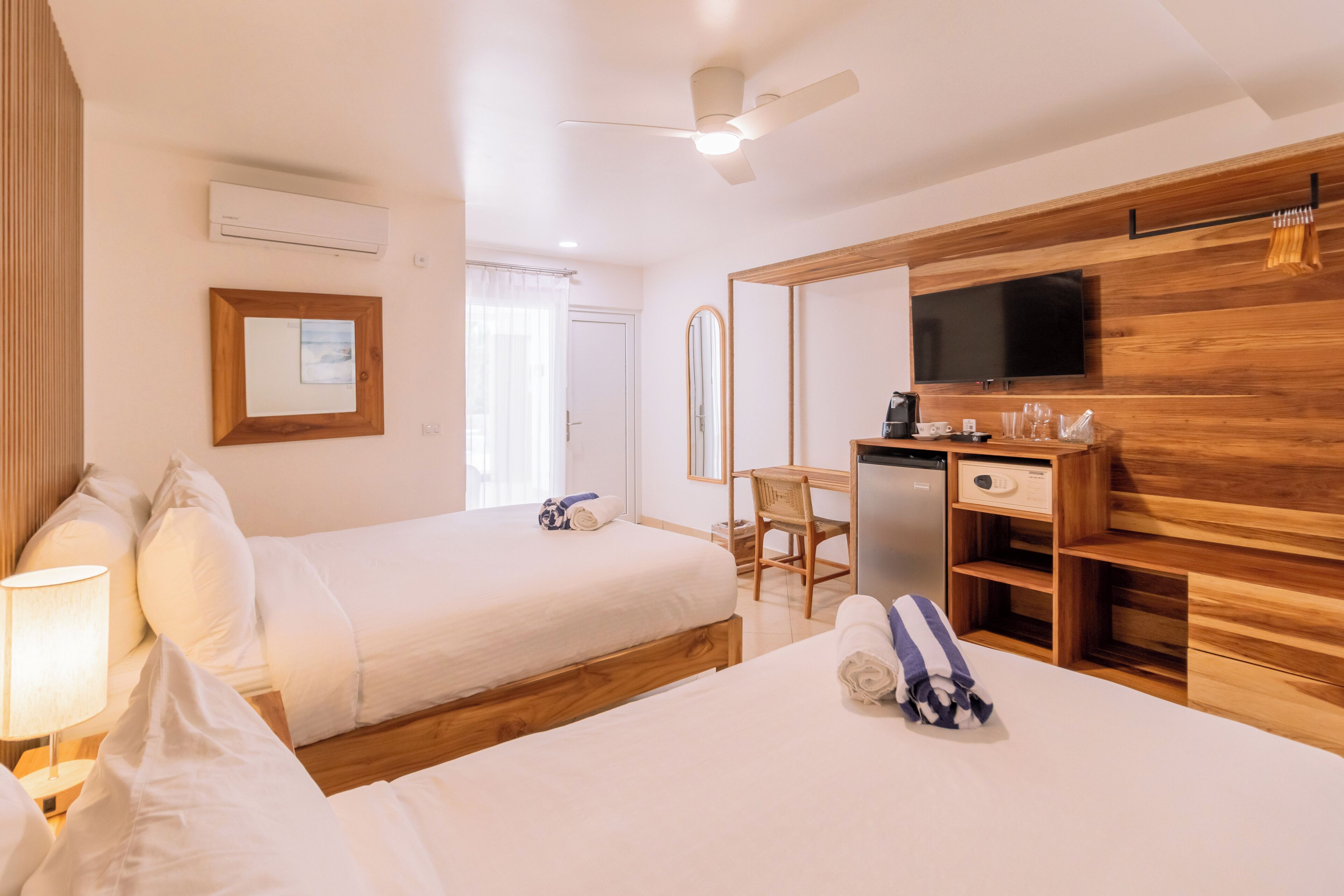 Une chambre d’hôtel avec deux lits, un bureau avec une télévision, une chaise et un miroir.