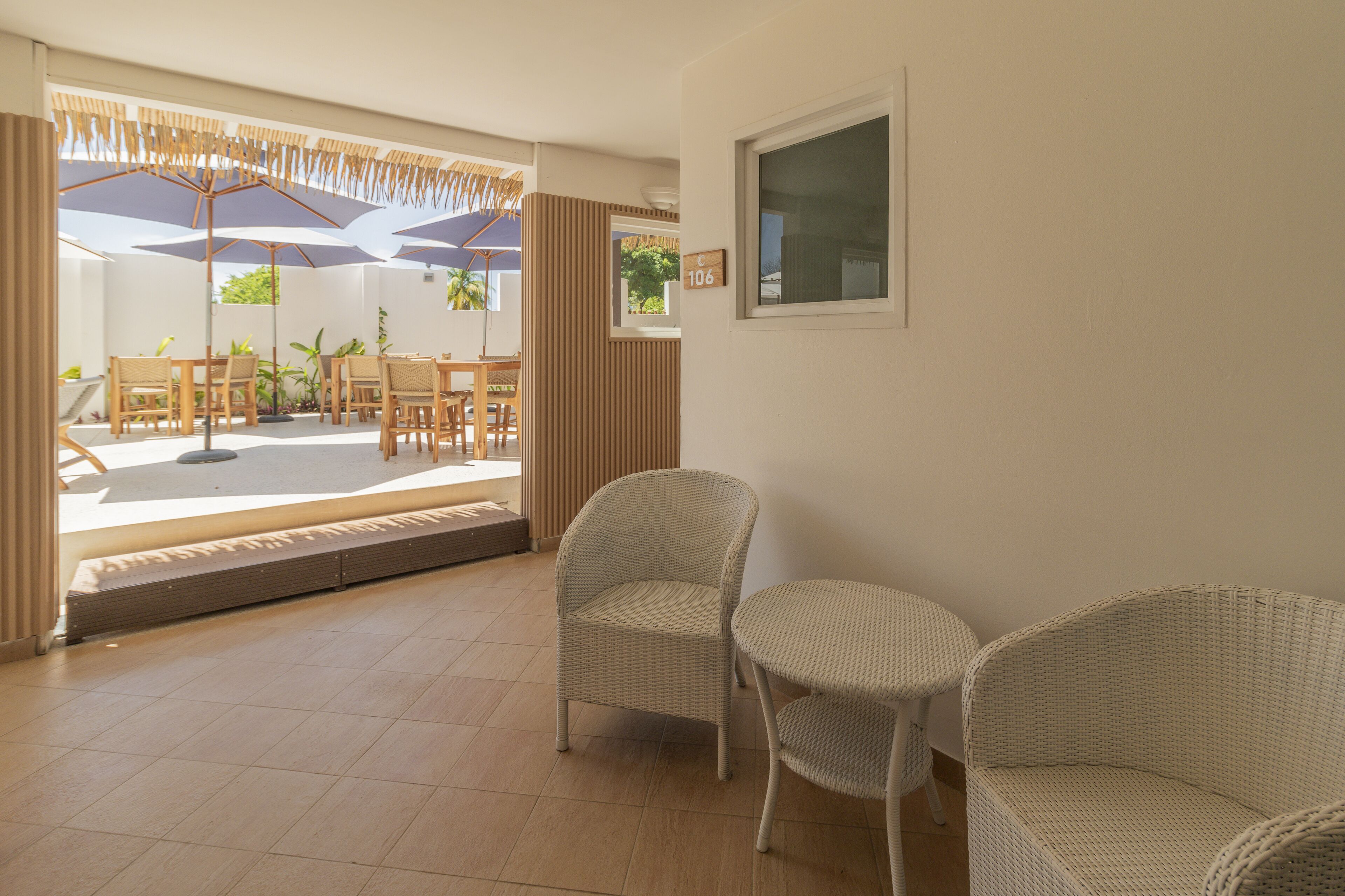 A spacious room with wicker furniture, a large window, and a door leading outside.