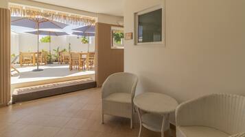 A spacious room with wicker furniture, a large window, and a door leading outside.