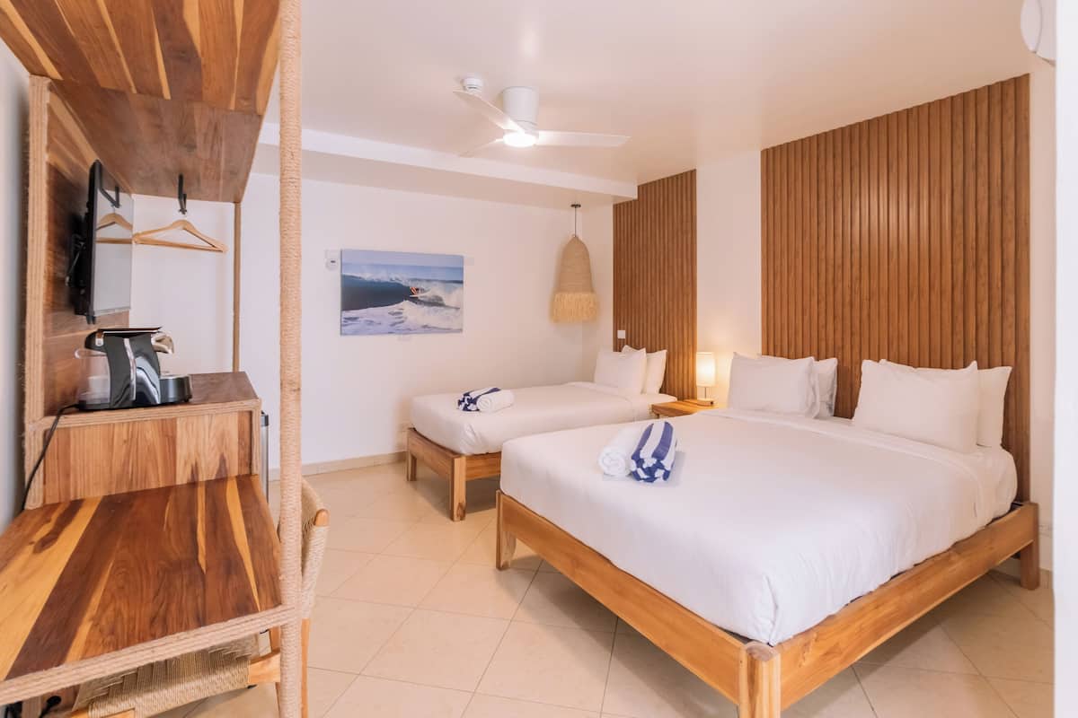 A hotel room with a wooden bed, a desk, a chair, a television, and a painting on the wall.