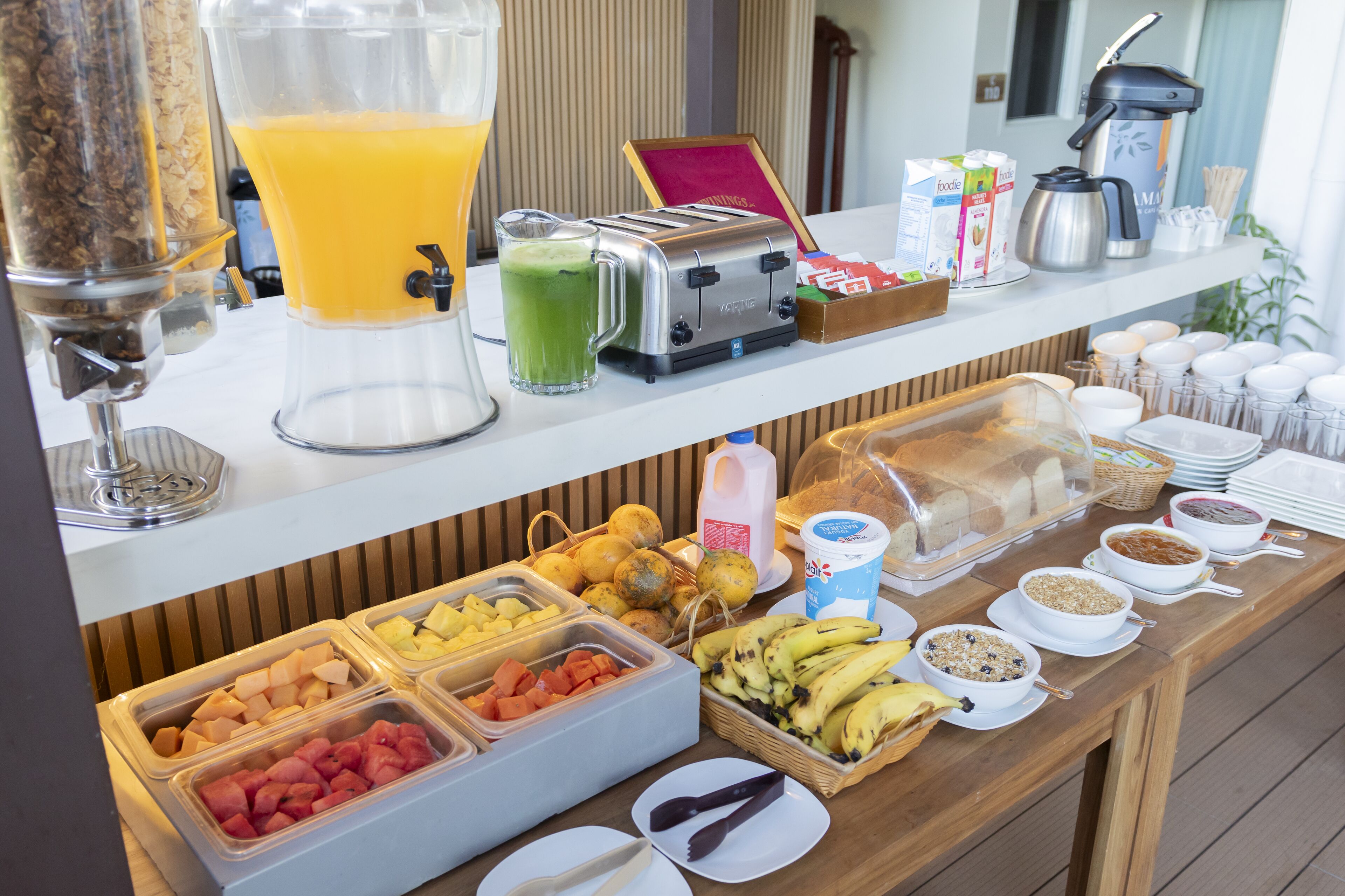 A buffet with various food items, a juice dispenser, and a coffee maker.