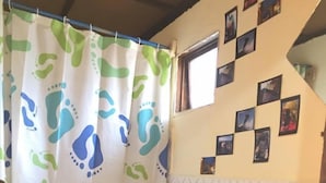 Een badkamer met toilet, wastafel, douchegordijn met voetprintpatroon en een muur versierd met kleine foto's.