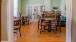 A dining area with a wooden table and chairs, a kitchen area with a stove and cabinets, and a living room with a couch.