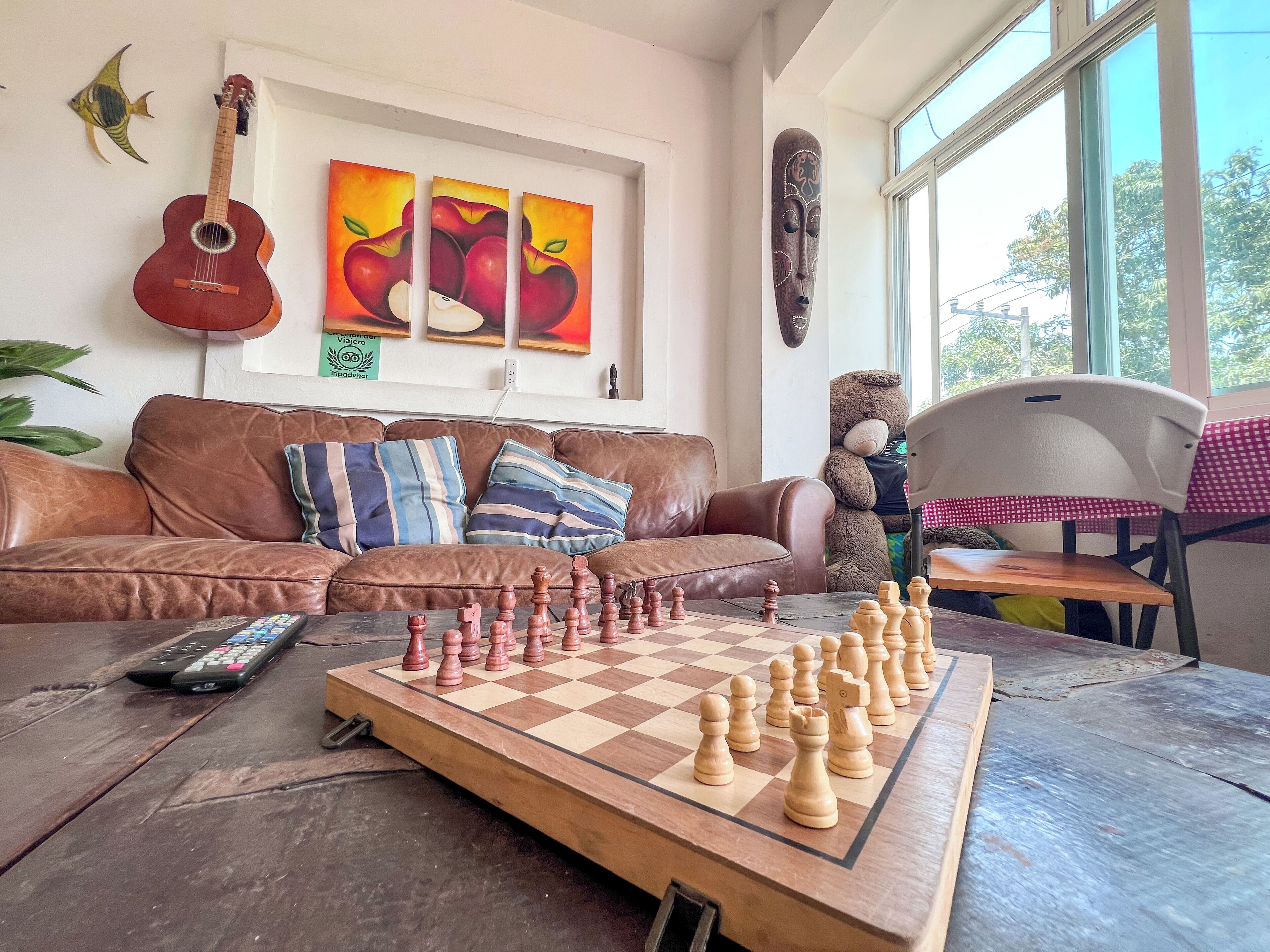 A living room with a chessboard, a guitar, and artwork on the wall.