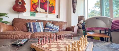 A living room with a chessboard, a guitar, and artwork on the wall.