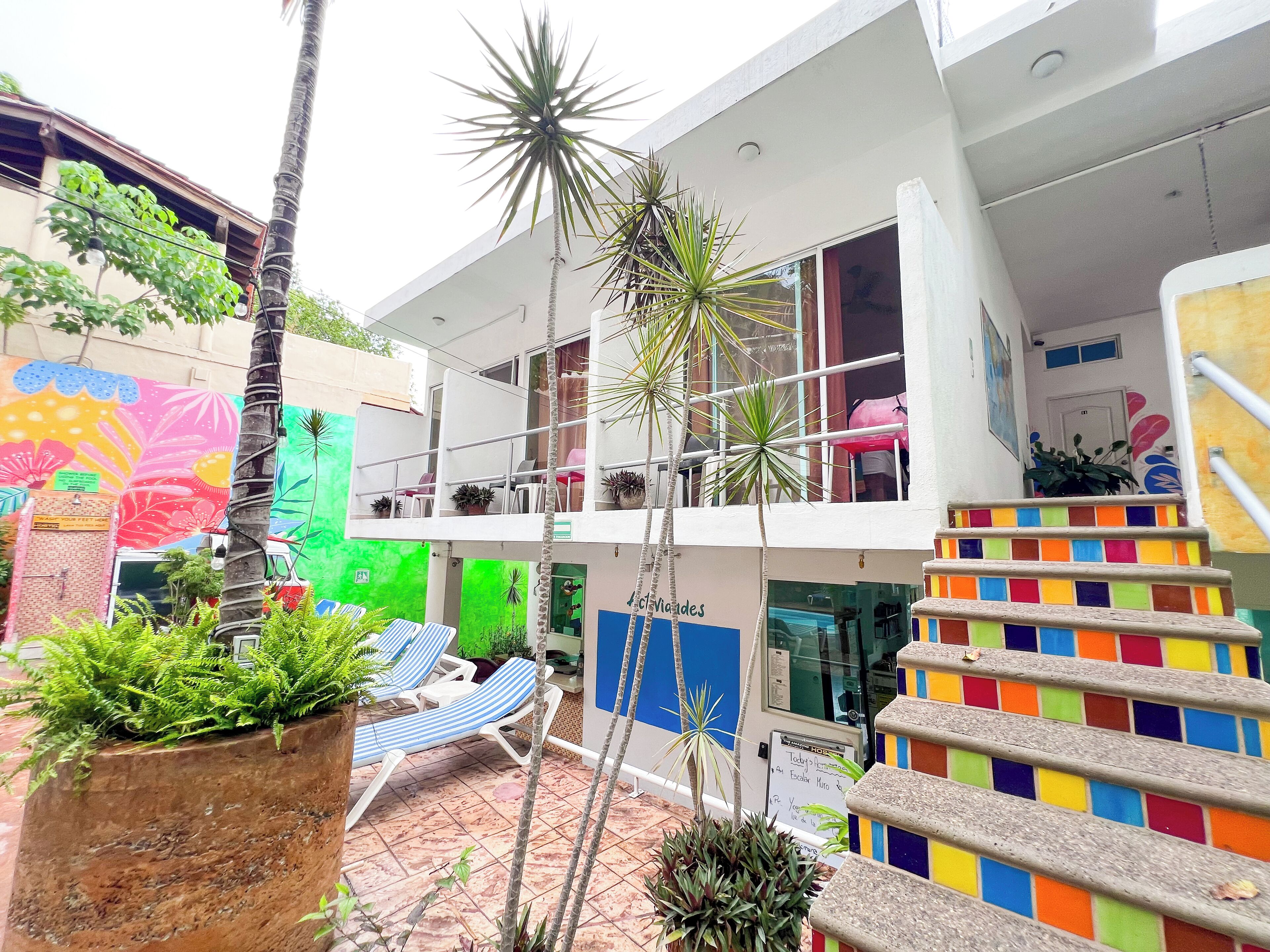 A multi-level building with a colorful staircase, outdoor seating area, and various plants.