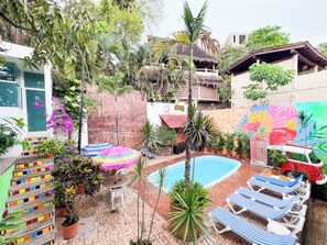 Relax by the pool surrounded by lush greenery and vibrant artwork.