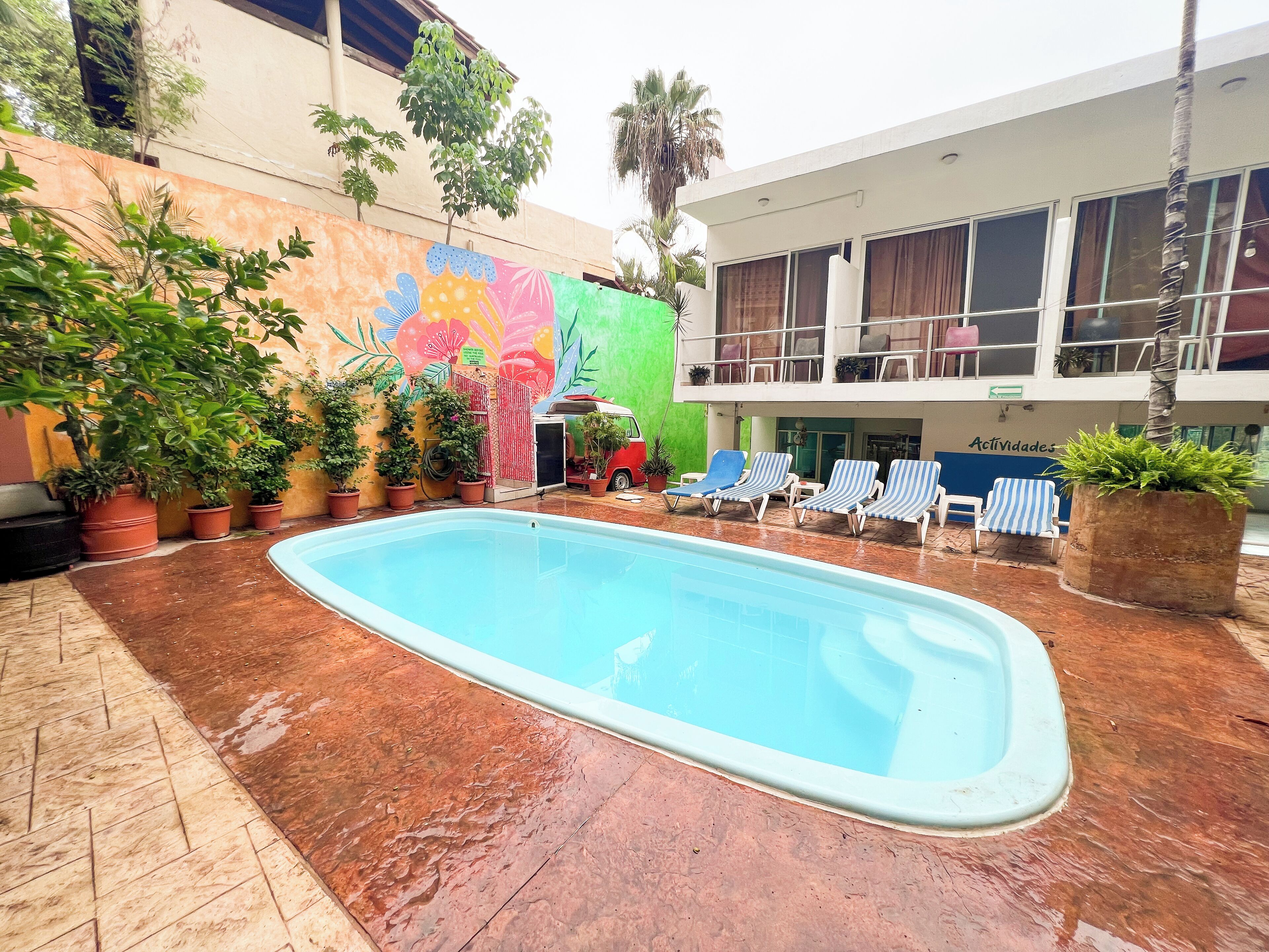 An outdoor swimming pool with lounge chairs and potted plants.