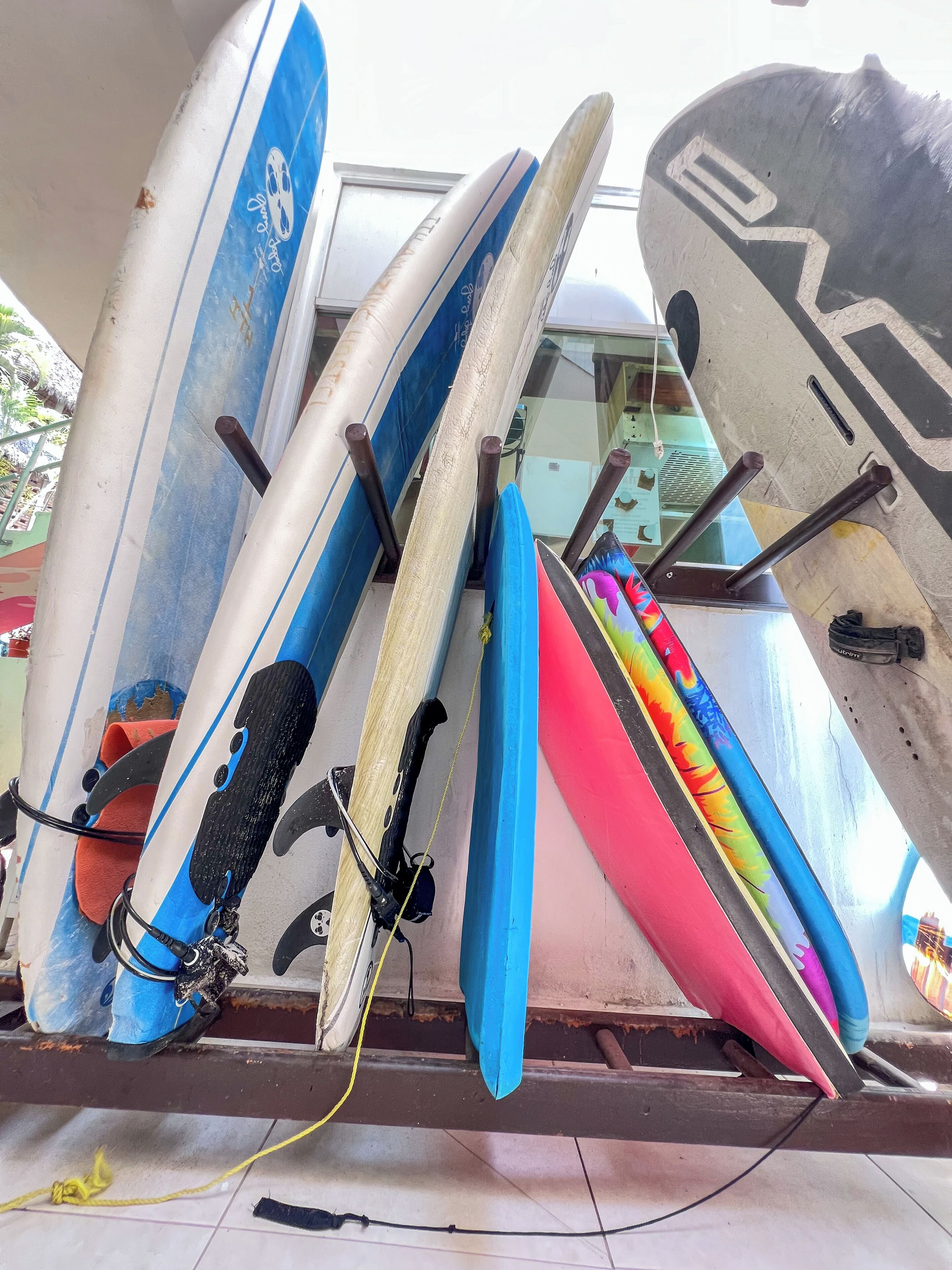 Surfbretter an einer Wand lehnen, einige weisen Gebrauchsspuren auf.