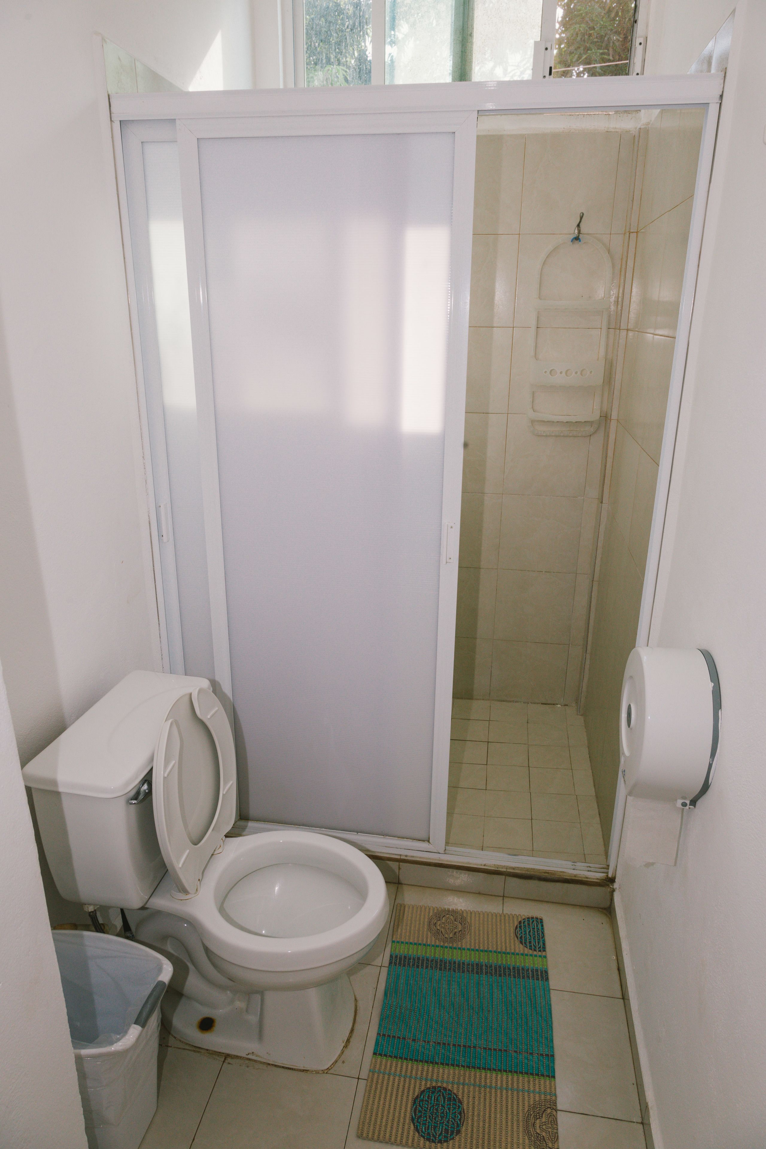 Un baño pequeño y funcional con inodoro, cabina de ducha y cubo de basura.