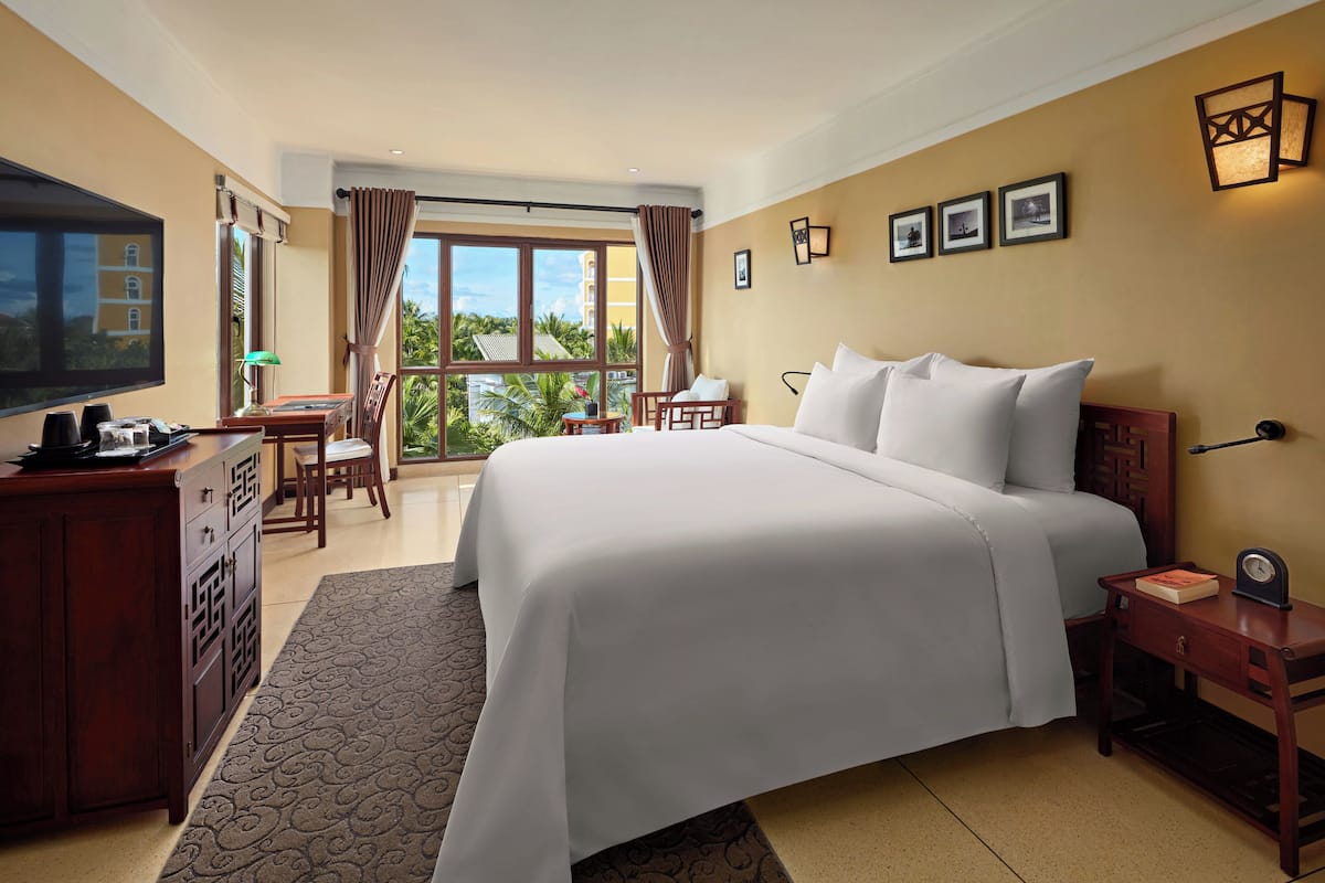 Una habitación de hotel con una cama grande, un escritorio, televisión y vistas al exterior.