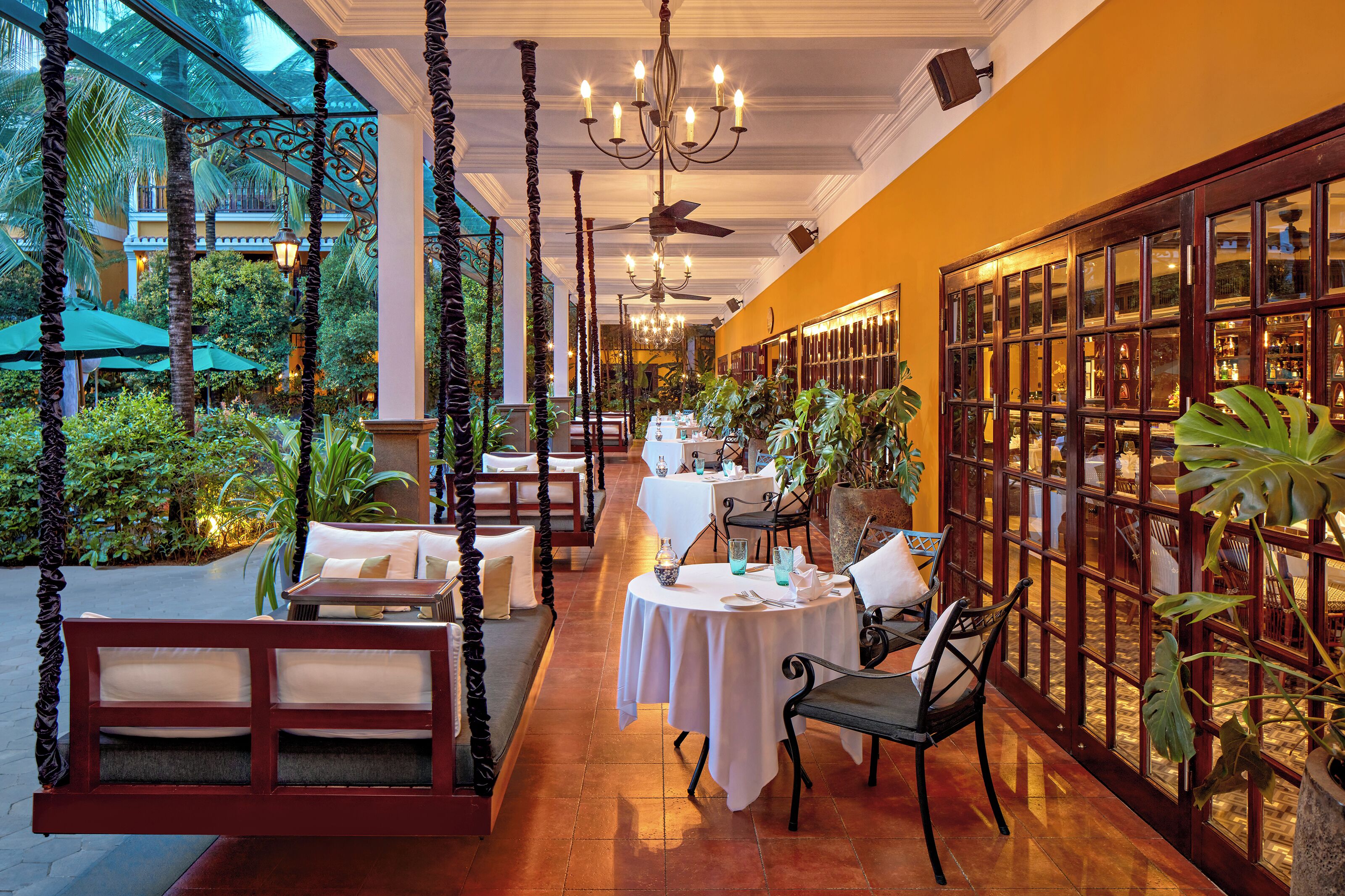 Un restaurante con mesas en el interior, una estructura de cristal y vistas al exterior.