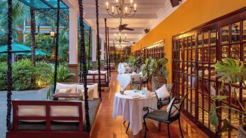 Un restaurante con mesas en el interior, una estructura de cristal y vistas al exterior.